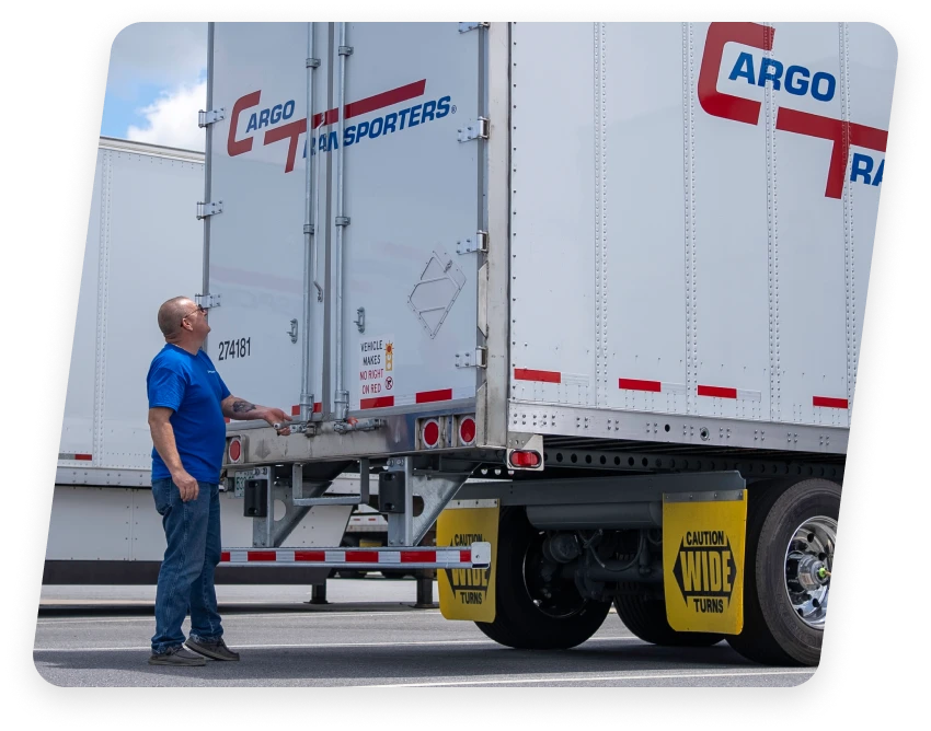 Worker next to a large white cargo trailer of a dedicated trucking company in North and South Carolina.