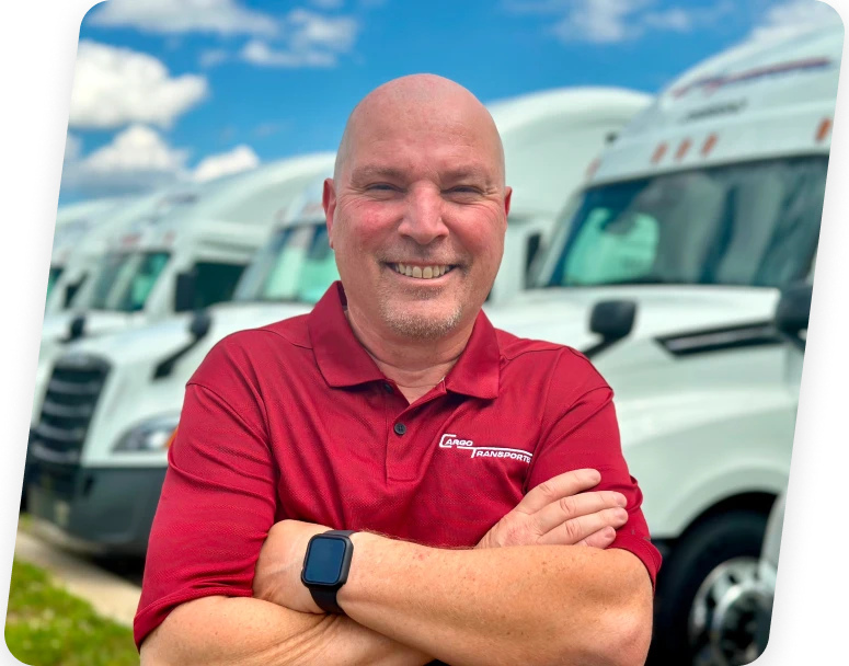 Cargo Transporters fleet manager stands in front of dedicated trucking company trucks in North Carolina yard