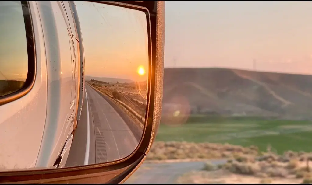 Truck rearview mirror reflecting uncertainty in freight logistics due to changing tariff policies.