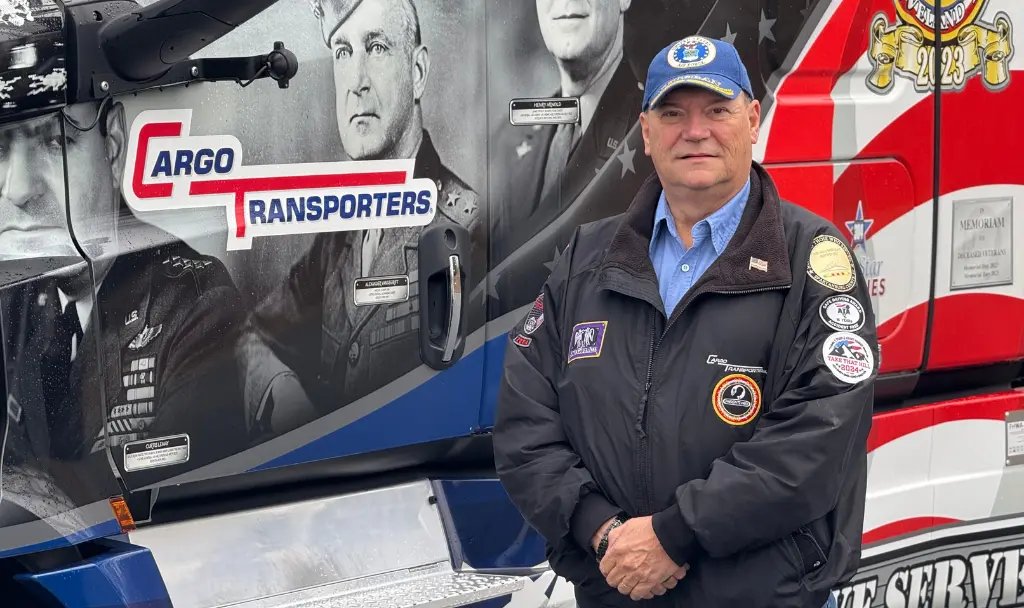 Perry Carter standing beside cargo transportation truck with veteran tribute