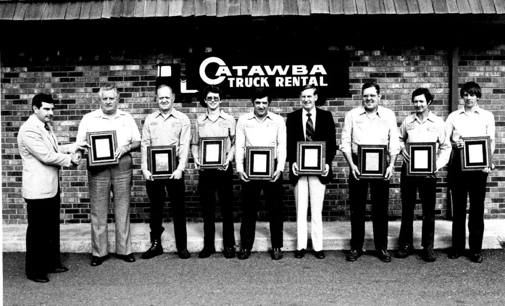 Catawba Truck Rental employees receiving recognition awards outside company office in Claremont, NC